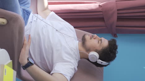 Vertical-video-of-Man-looking-out-the-window-and-listening-to-music-with-headphones.